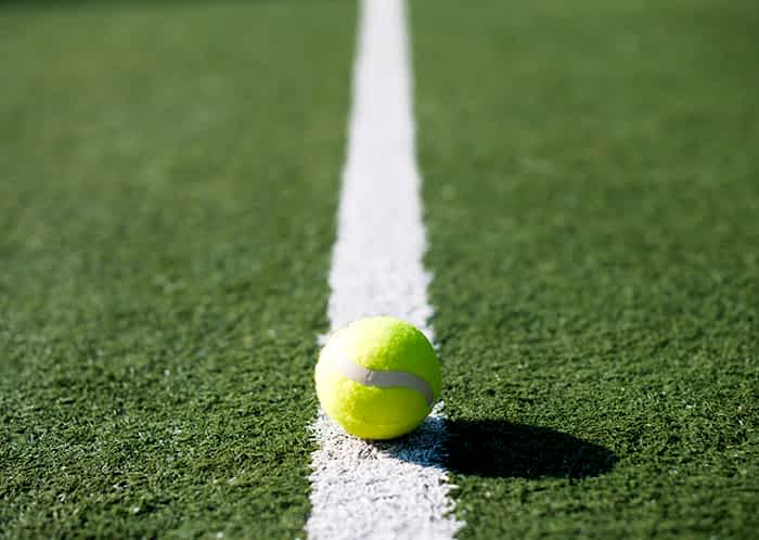 Mantenimiento de una cancha de tenis de césped artificial con relleno de arena